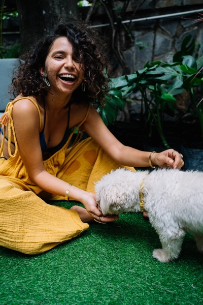 A woman in a yellow dress playing with a dog